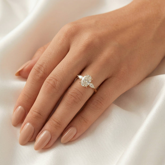 Oval cut moissanite three stone engagement ring with pear sides on a knife edge yellow gold band, view 2
