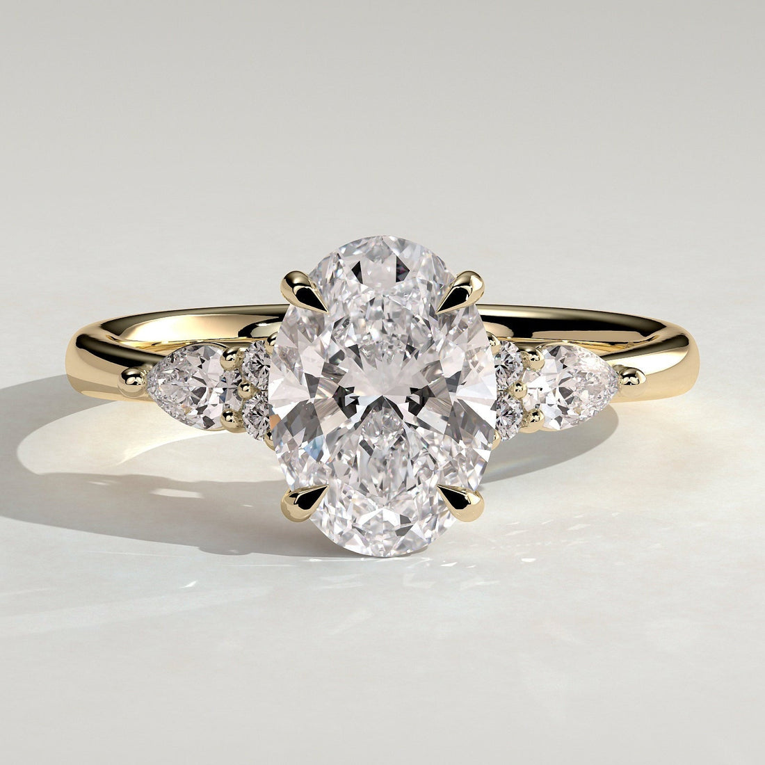 Oval cut moissanite engagement ring with pear and round cluster shoulders in yellow gold