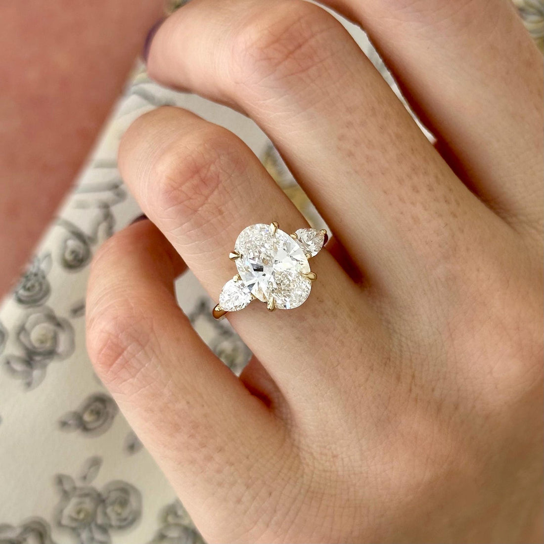 Oval cut moissanite three stone engagement ring with pear side stones in yellow gold