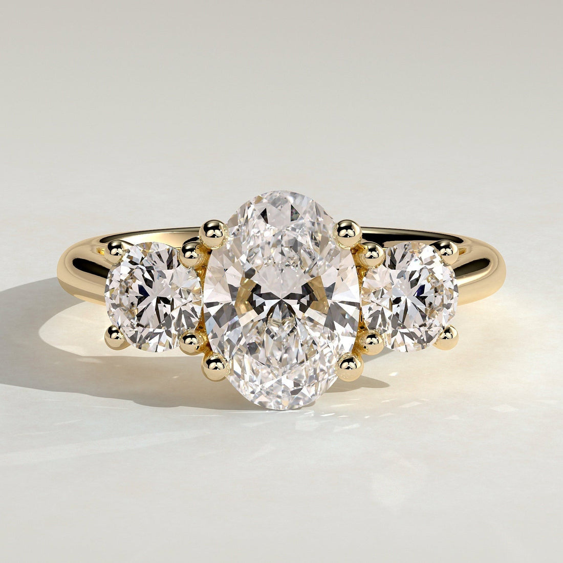 Oval cut moissanite three stone engagement ring with round side stones in yellow gold