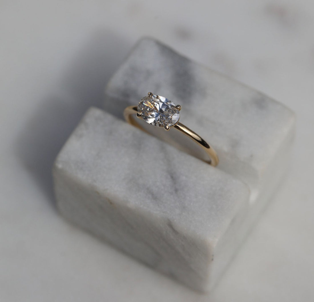 Oval cut moissanite four claw solitaire engagement ring on a round wire yellow gold band