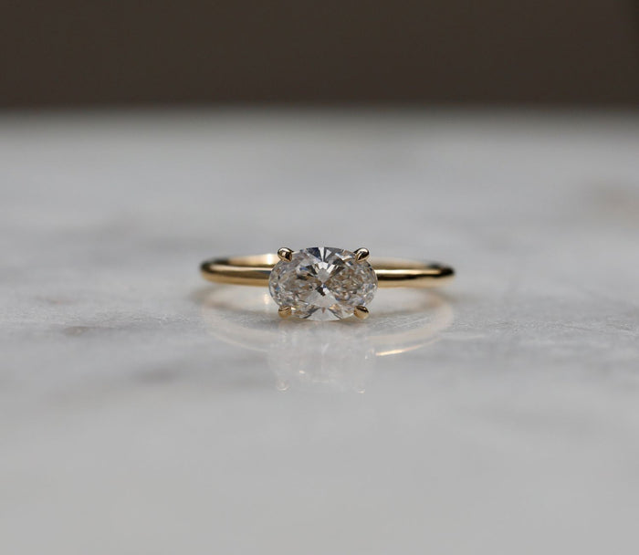 Oval cut moissanite four claw solitaire engagement ring on a round wire yellow gold band, view 2