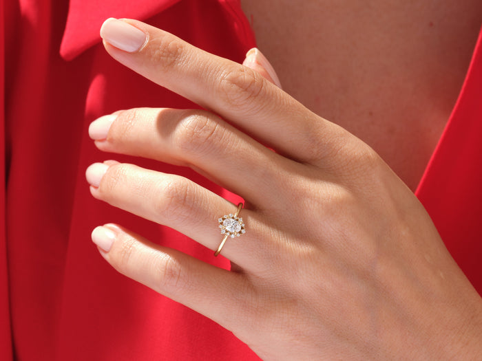 Oval moissanite sunburst halo ring in yellow gold worn on the hand