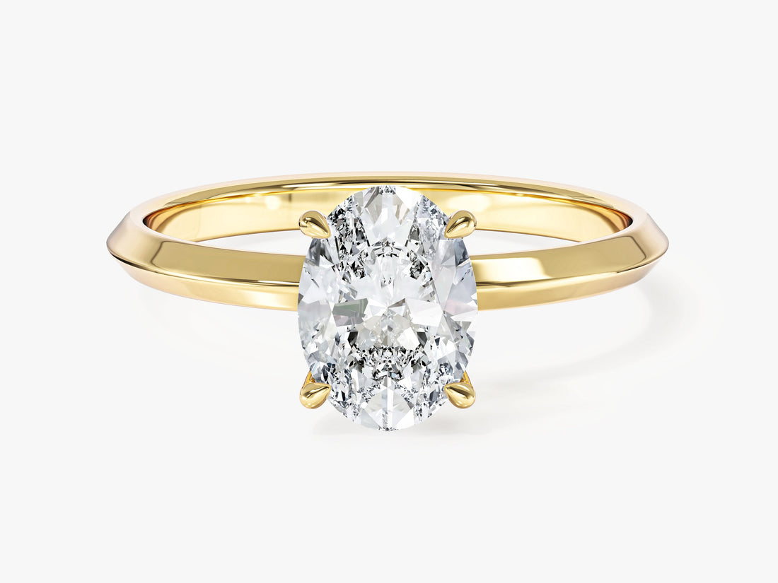 Dainty oval moissanite four claw solitaire on a slim knife edge band in 14K yellow gold, front view