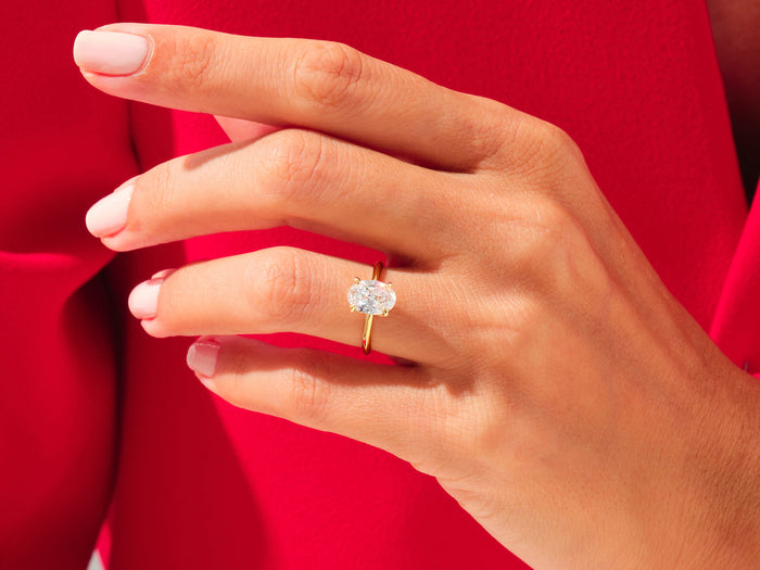 Oval moissanite statement solitaire in yellow gold worn on the ring finger