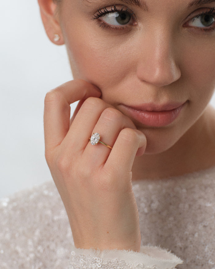 Oval lab grown diamond solitaire ring worn on the hand held to the chin