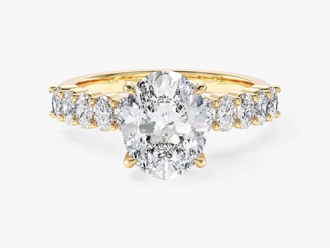 Oval moissanite engagement ring with oval side stones on a shared prong band in yellow gold, front view