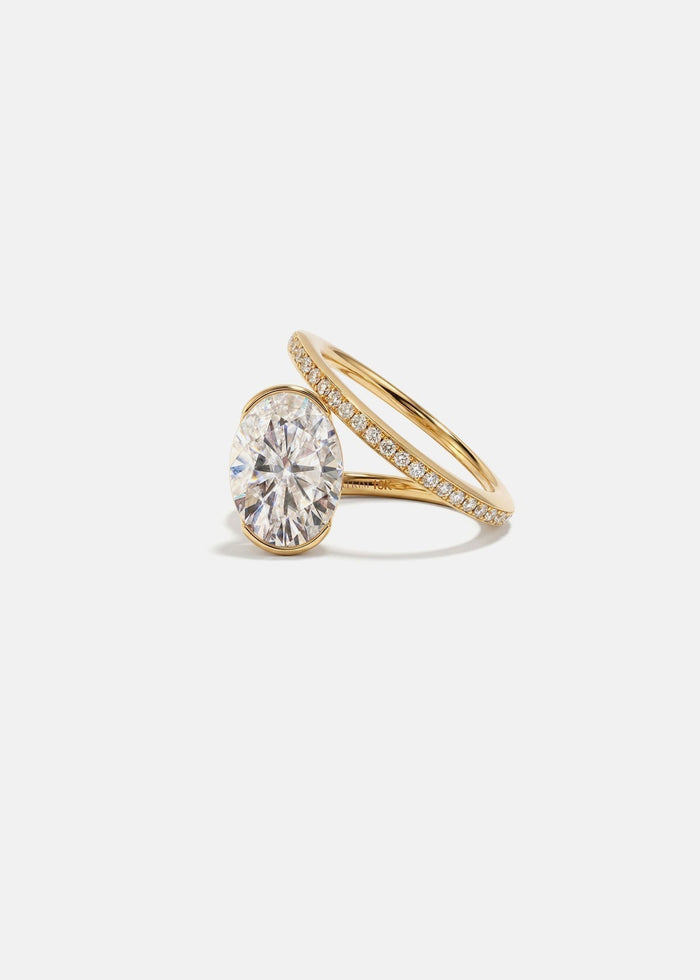 Oval cut moissanite bezel set engagement ring on a spiral pave band in yellow gold