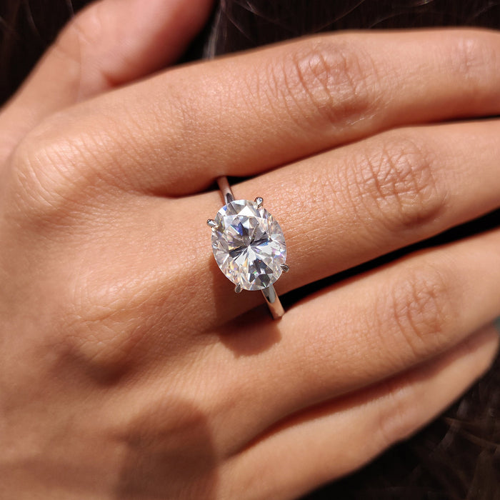 Oval cut moissanite tapered cathedral solitaire engagement ring on a plain white gold band, view 2