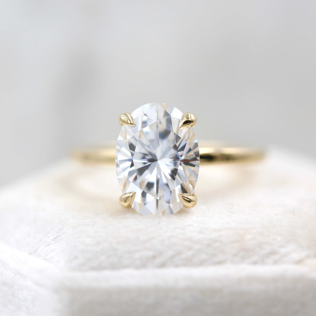 Oval cut moissanite teardrop claw solitaire engagement ring on a hairline yellow gold band