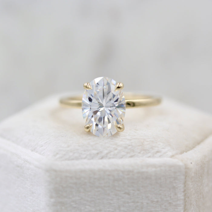 Oval cut moissanite teardrop claw solitaire engagement ring on a hairline yellow gold band, view 2