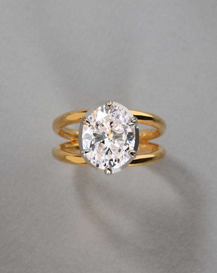 Oval cut moissanite in a white head on a two tone double shank in yellow gold, view 2