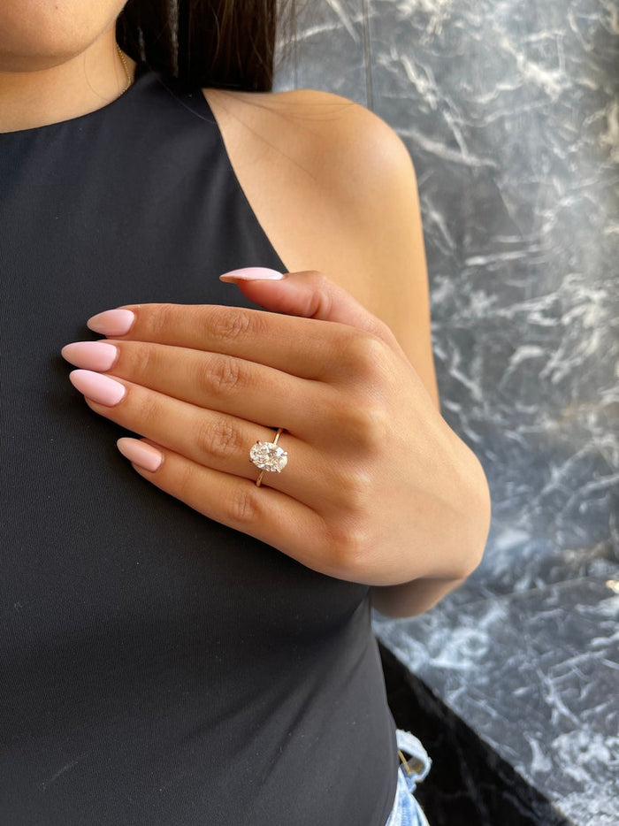 Oval cut moissanite solitaire engagement ring on a tapered knife edge rose gold band, view 2