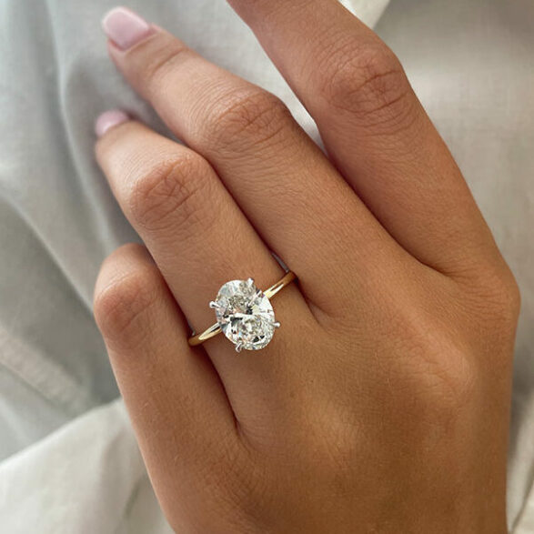 Oval cut moissanite solitaire engagement ring on a tapered plain yellow gold band