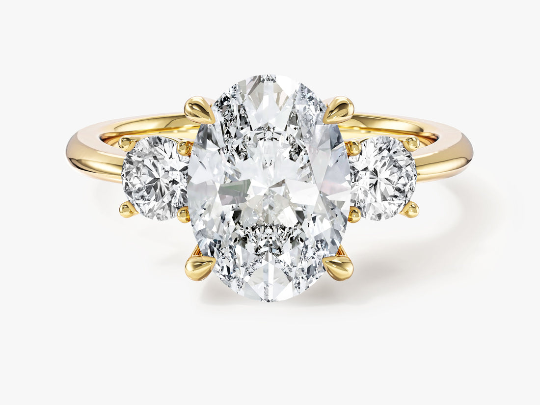 Oval moissanite three stone engagement ring with round side stones in 14K yellow gold, front view