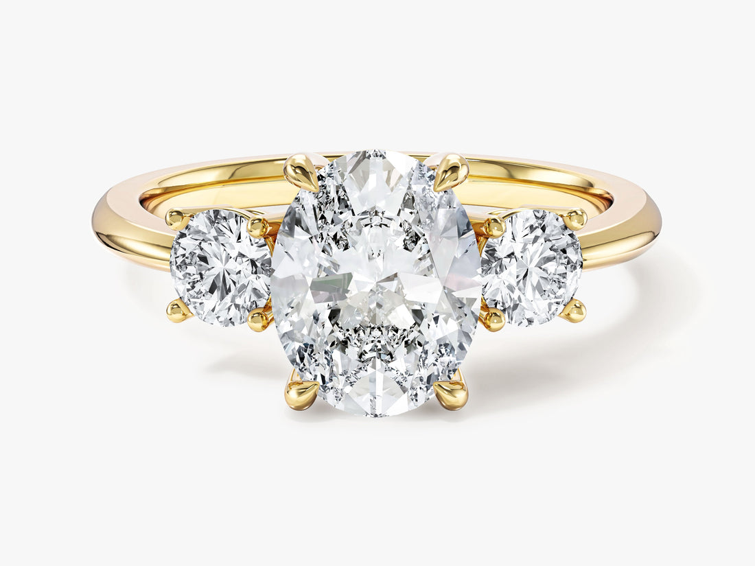 Classic oval moissanite trilogy engagement ring with two round side stones in 14K yellow gold, front view
