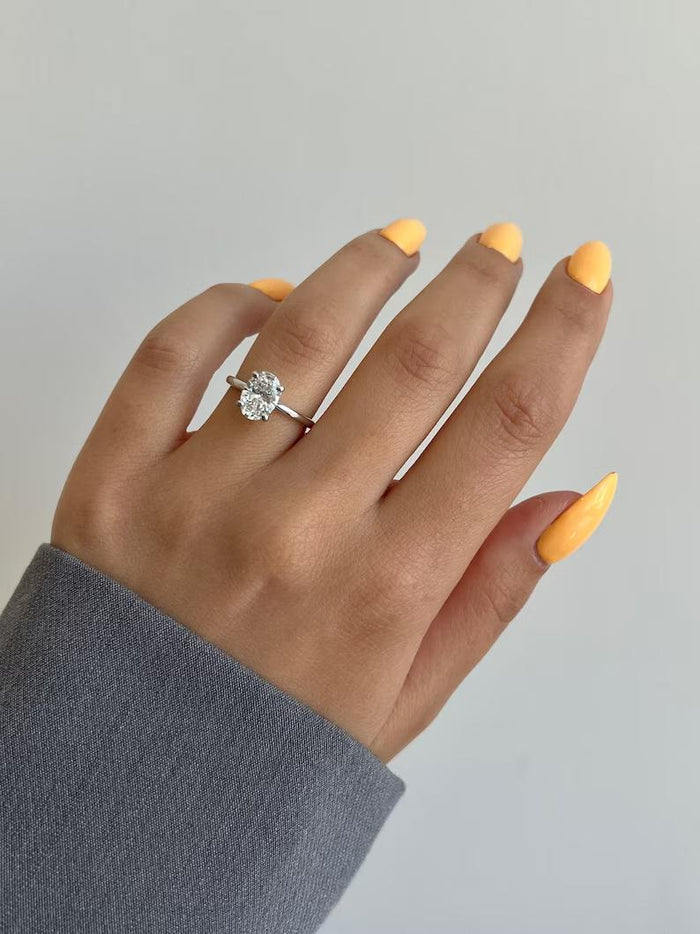 Oval cut moissanite in a two tone basket setting on a plain band, view 2