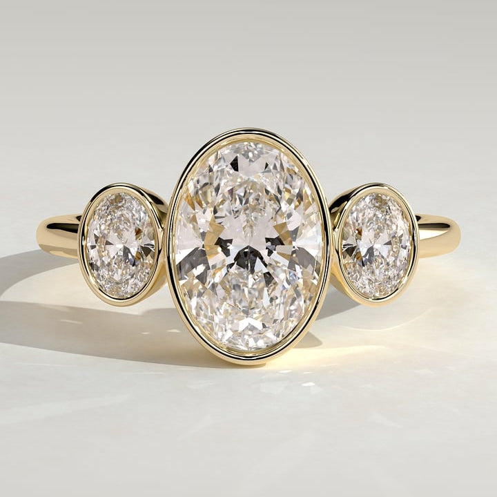 Oval cut moissanite three stone full bezel engagement ring in yellow gold