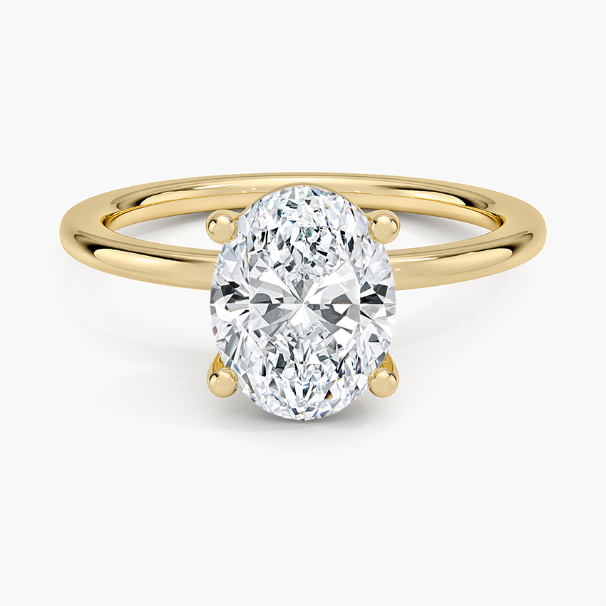 Oval moissanite in ball tipped prongs on a fine yellow gold wire band, top view