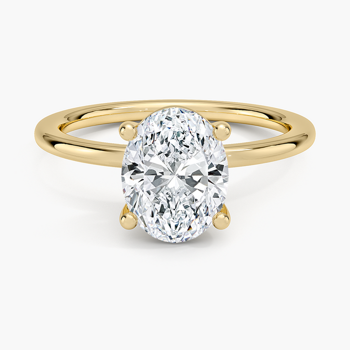 Oval moissanite in ball tipped prongs on a fine yellow gold wire band, top view