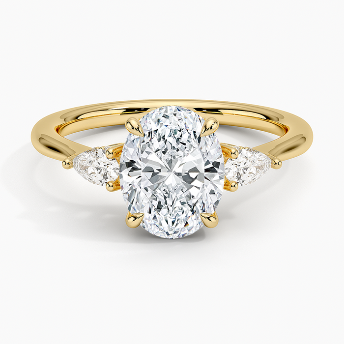 Oval moissanite three stone ring with pear side stones in yellow gold, top view