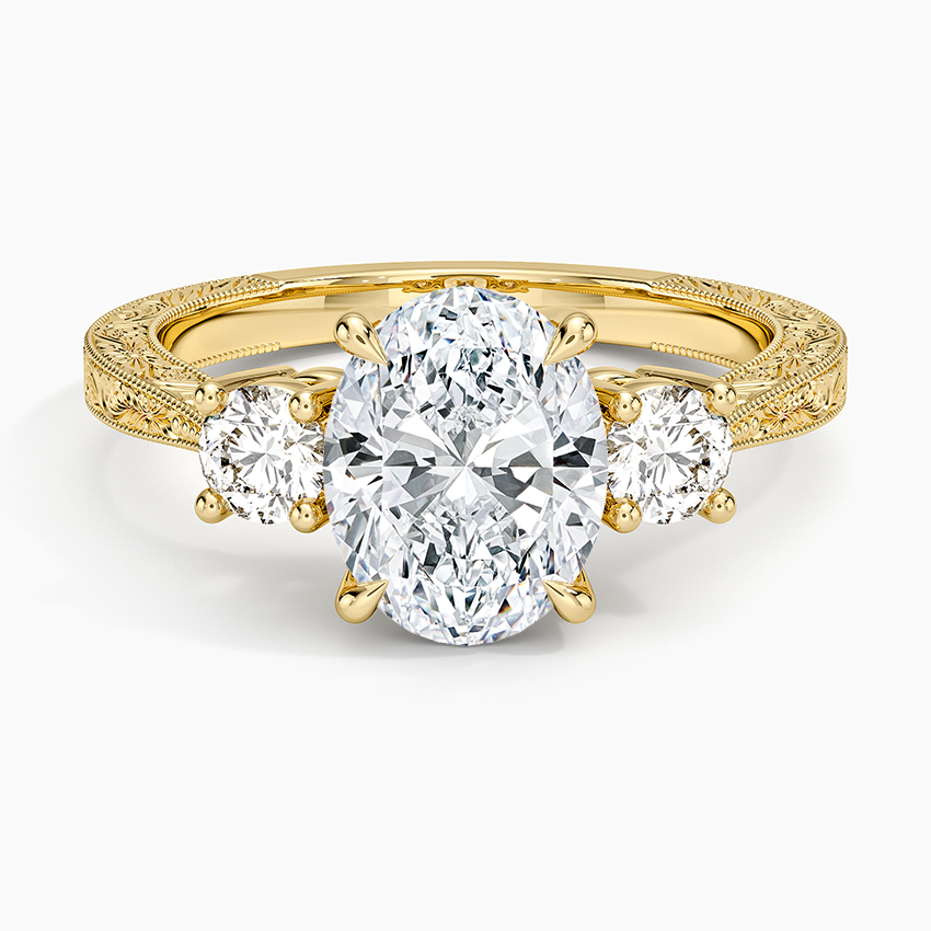 Oval moissanite three stone ring on a hand engraved yellow gold band, top view