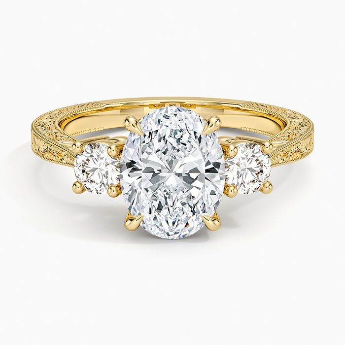 Oval moissanite three stone ring on a hand engraved yellow gold band, top view