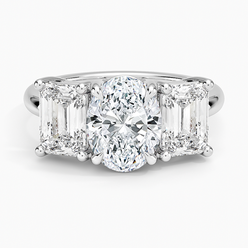 Oval moissanite three stone ring with east west emerald cut side stones in white gold, top view