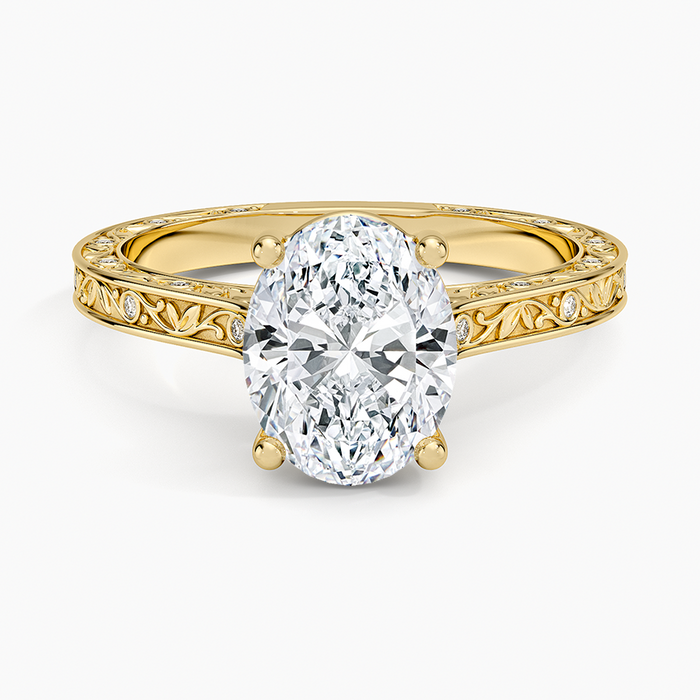 Oval moissanite on an engraved vine band with flush set accents in yellow gold