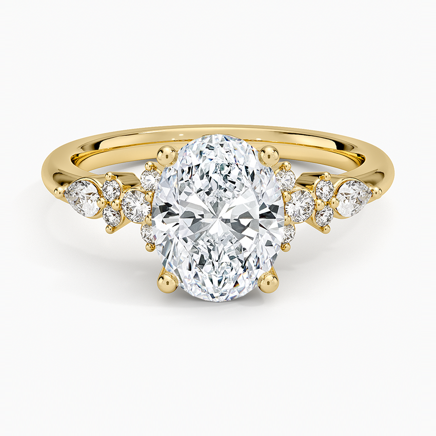 Oval moissanite engagement ring with graduated round and pear cluster in yellow gold