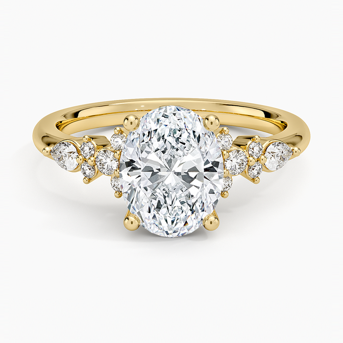 Oval moissanite engagement ring with graduated round and pear cluster in yellow gold