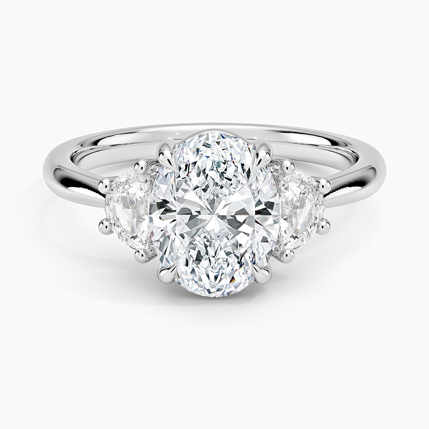 Oval moissanite with two half moon side stones on a plain white gold band, top view