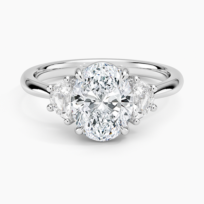 Oval moissanite with two half moon side stones on a plain white gold band, top view