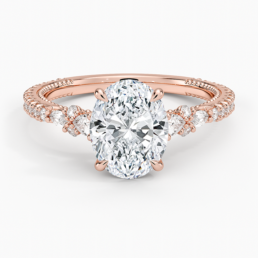 Oval moissanite with pear and round accent clusters on a milgrain pave rose gold band, top view