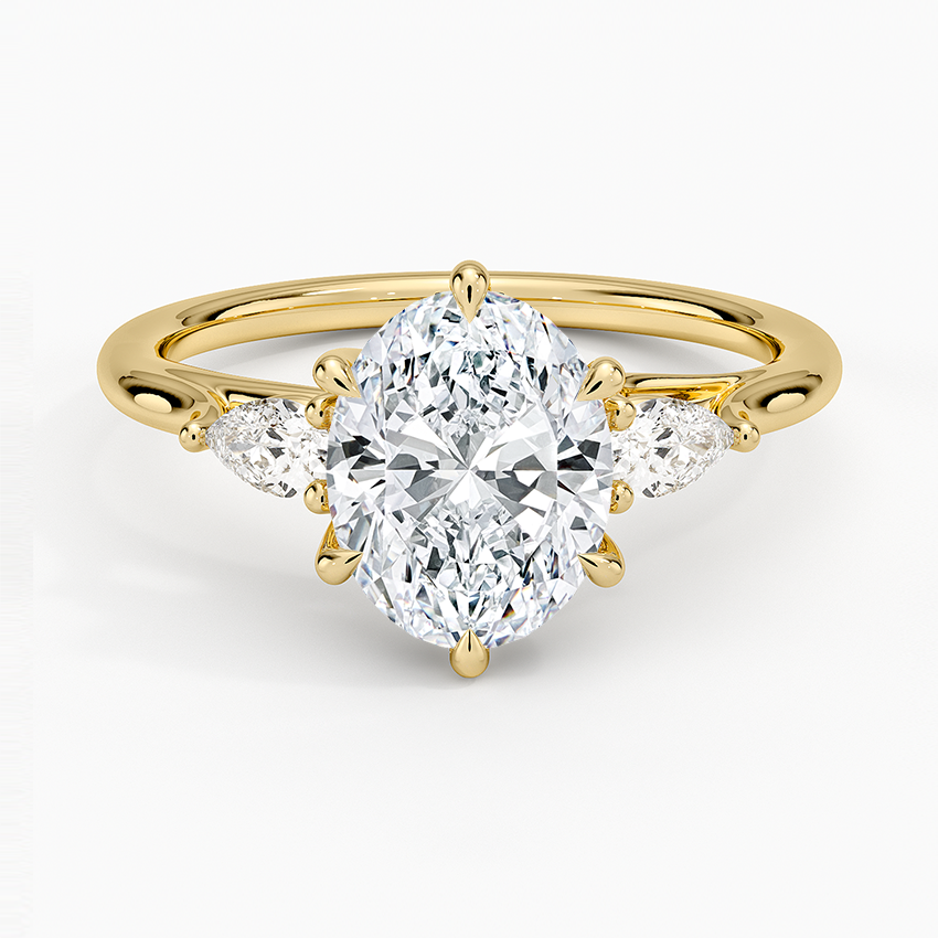 Oval moissanite three stone ring with outward facing pear side stones in yellow gold, top view