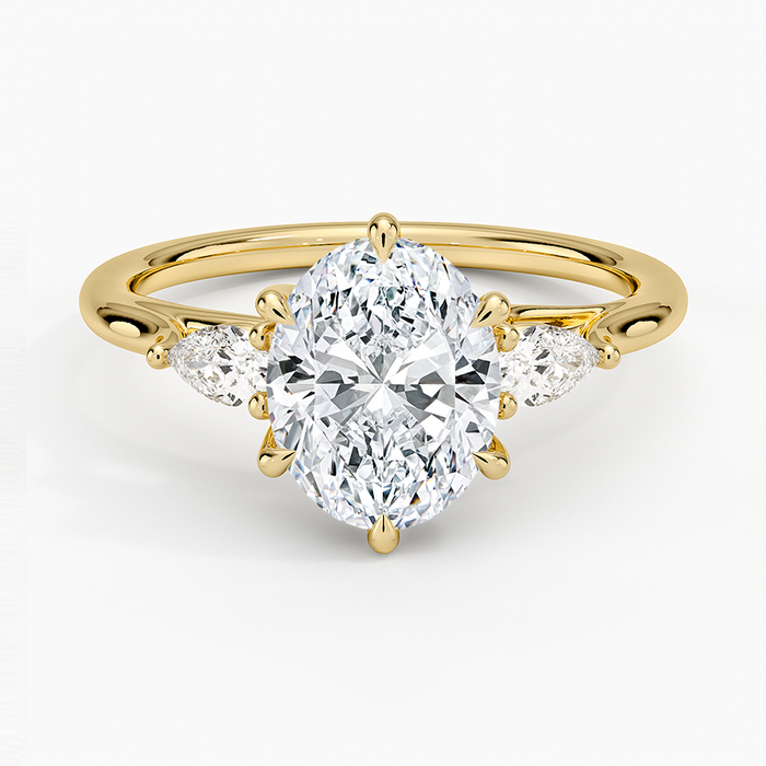 Oval moissanite three stone ring with outward facing pear side stones in yellow gold, top view