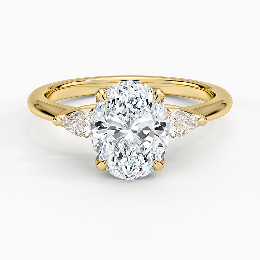 Oval moissanite with pear cut side stones in yellow gold, top view