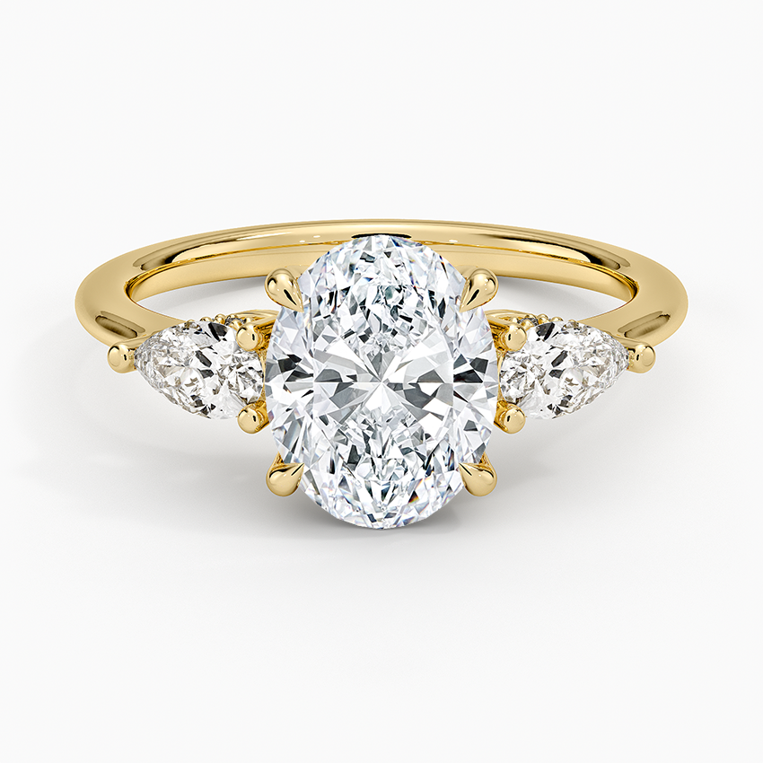 Oval moissanite with pear side stones on a fine yellow gold band, top view