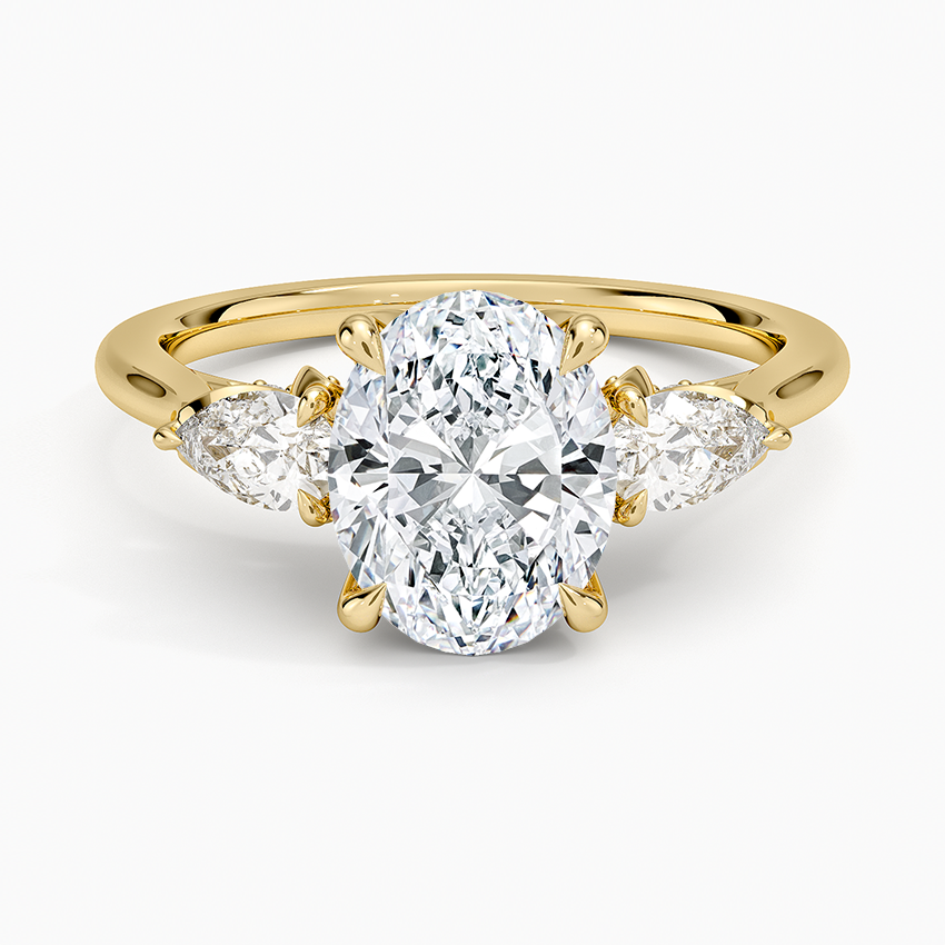 Oval moissanite with pear side stones on a notched yellow gold band, top view