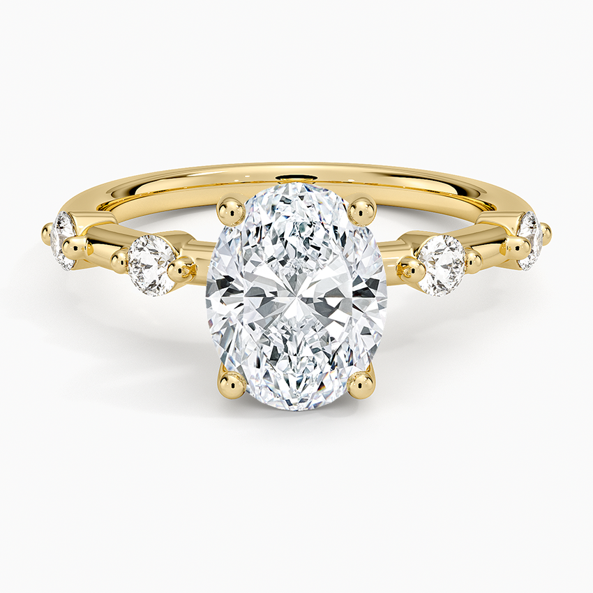 Oval moissanite with spaced round accents on a yellow gold band, top view