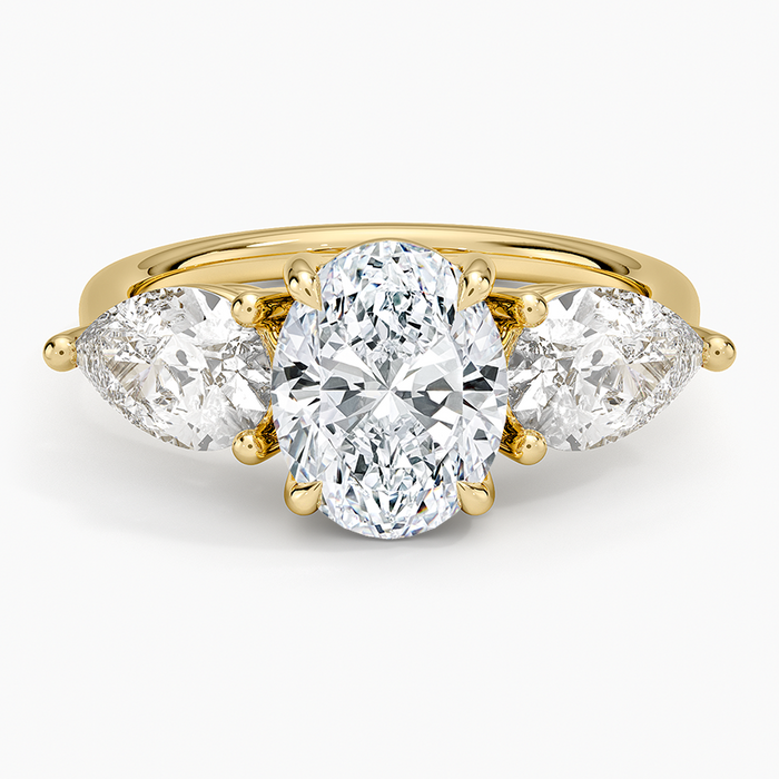 Oval moissanite statement three stone ring with large pear sides in yellow gold, top view