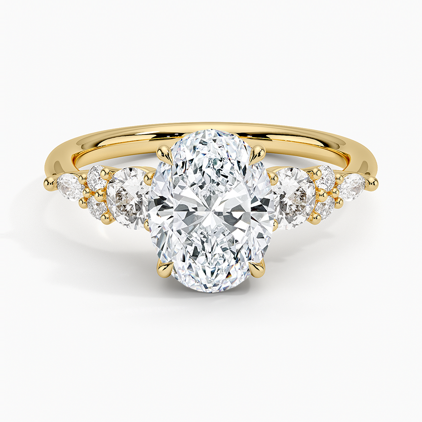 Oval moissanite ring with graduated round accent clusters on a plain yellow gold band, top view