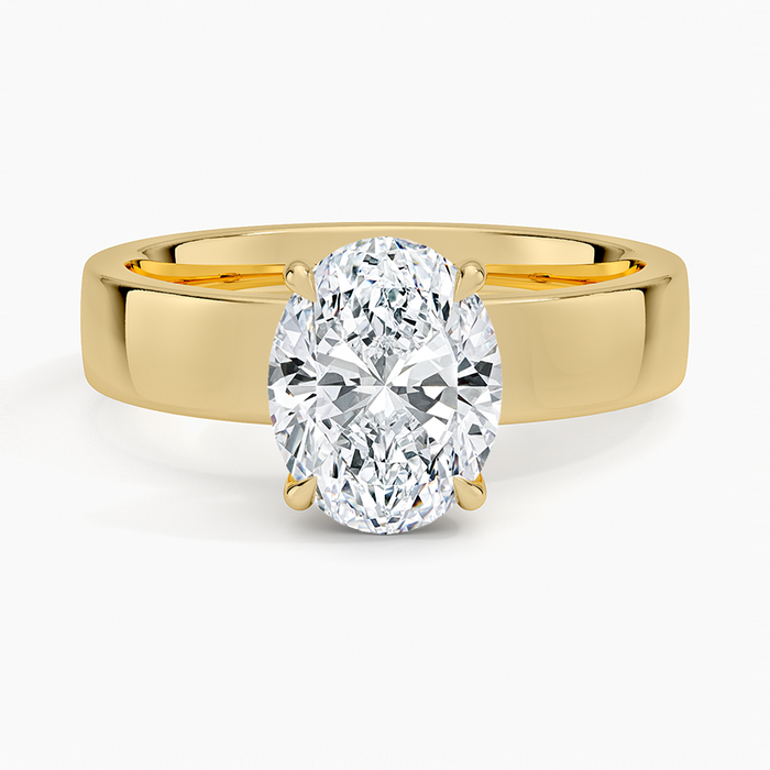 Oval moissanite solitaire on a wide flat yellow gold band, top view