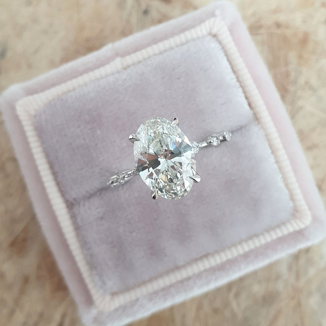 Oval cut moissanite engagement ring with widely spaced accents on a hairline white gold band