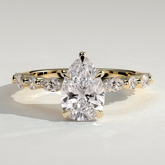 Pear cut moissanite engagement ring with alternating marquise and round accents in yellow gold