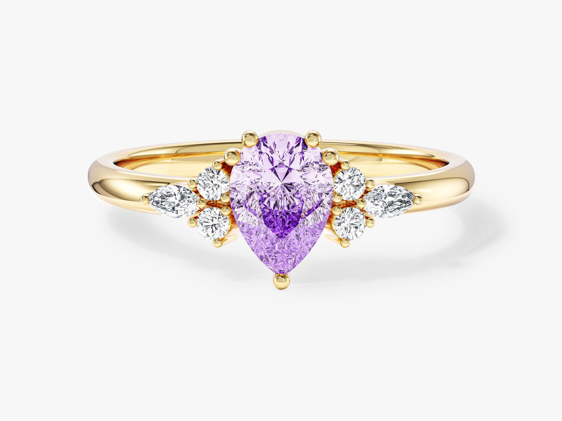 Pear cut moissanite cluster engagement ring with marquise and round accents in yellow gold, front view, shown with a lavender sample stone