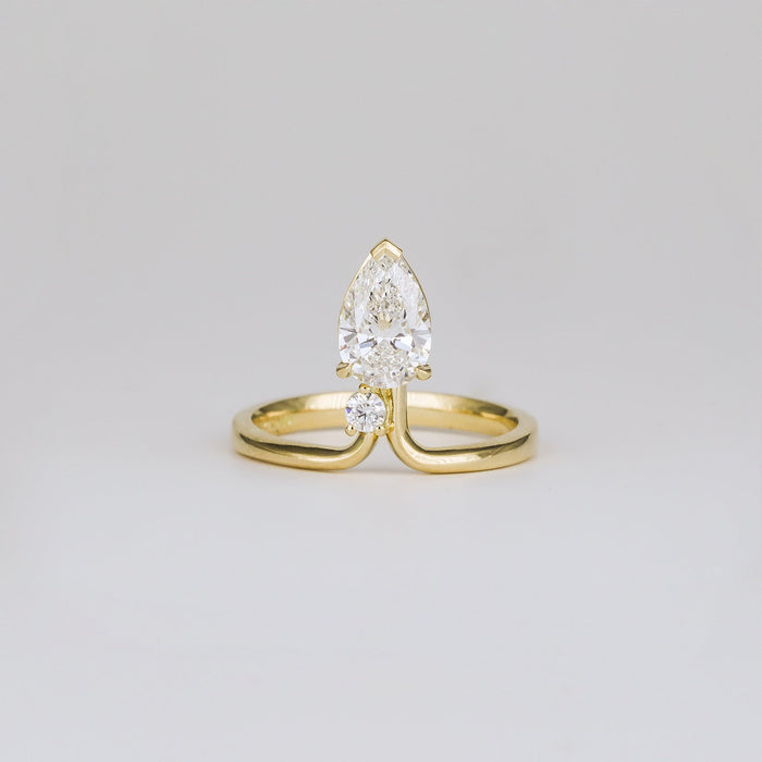 Pear cut moissanite chevron band engagement ring with a round accent in yellow gold