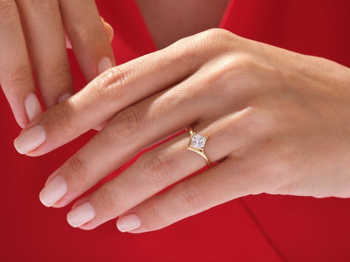 Princess cut lab grown diamond V band ring worn on the hand against a red dress
