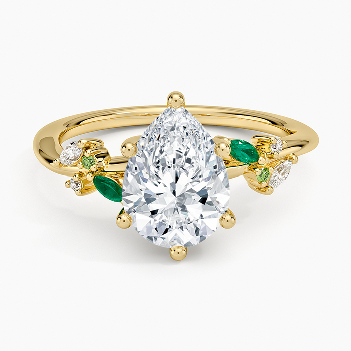 Pear cut moissanite with alternating green emerald and colorless marquise leaves in yellow gold, top view