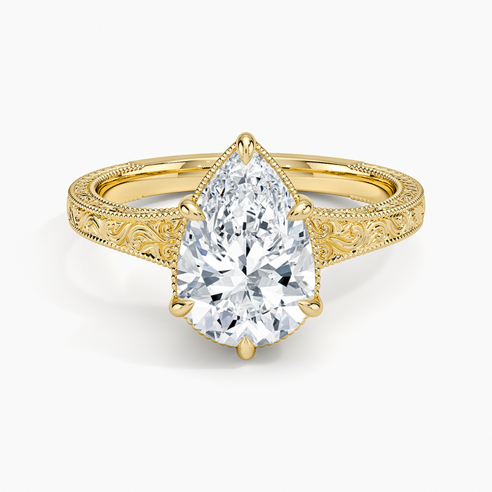 Pear cut moissanite above a hand engraved baroque scroll band with milgrain in yellow gold, top view